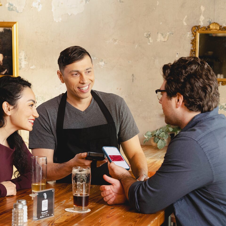 A server taking a phone payment at the table on a SpotOn handheld